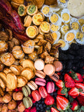 Breakfast platter with hard boiled eggs, bacon, sweet treats, fruit, croissants, butter and macaroons. 